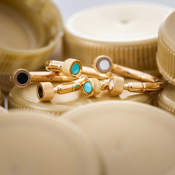 Stacked gold rings featuring colorful enamel charms in turquoise, white, and black