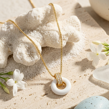 Close-up of a Jason Hyde white organic-shaped pendant on a gold box chain