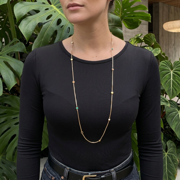 Long gold station necklace with colorful recycled plastic charms worn by a model.