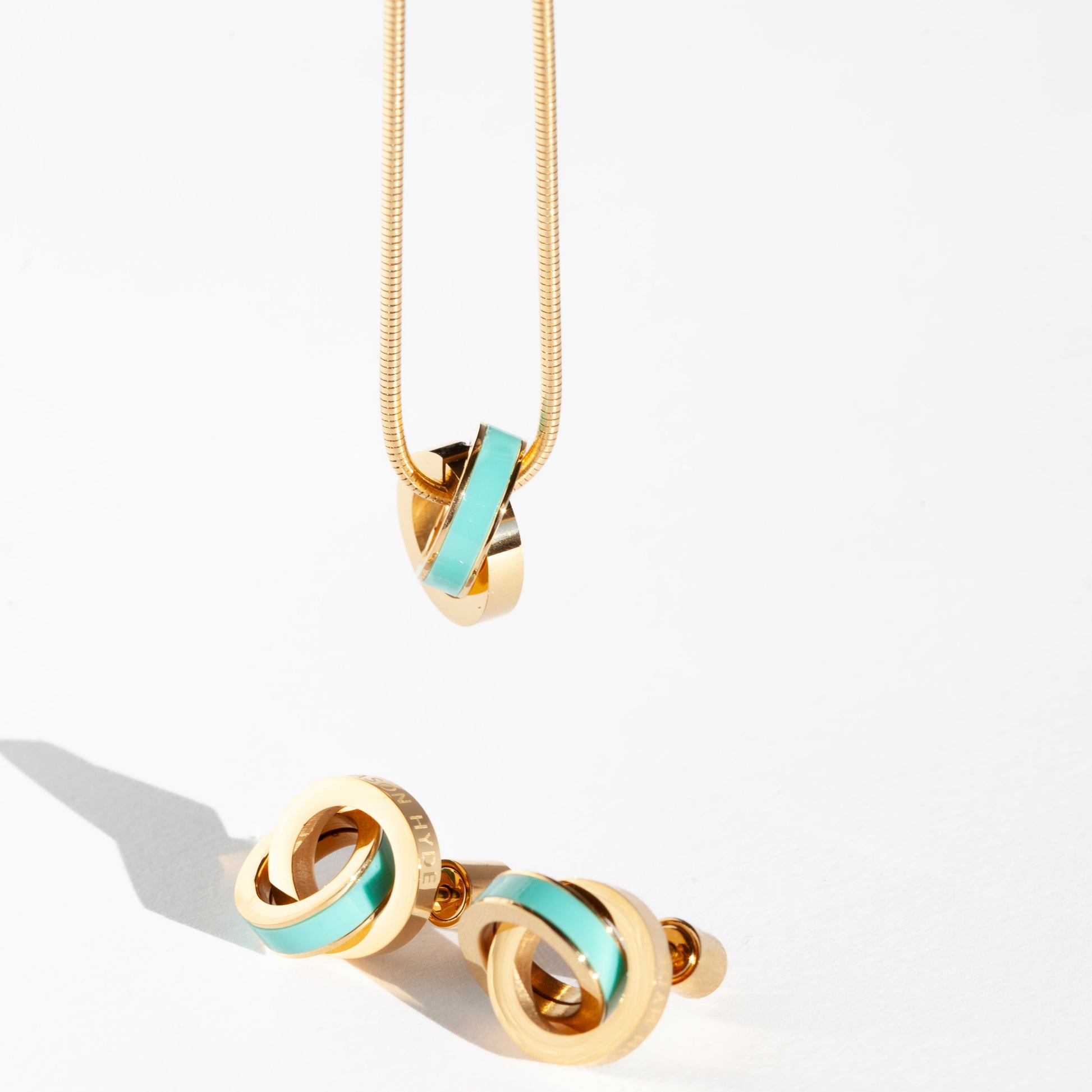 Gold stud earrings and a matching necklace with swirling turquoise charm