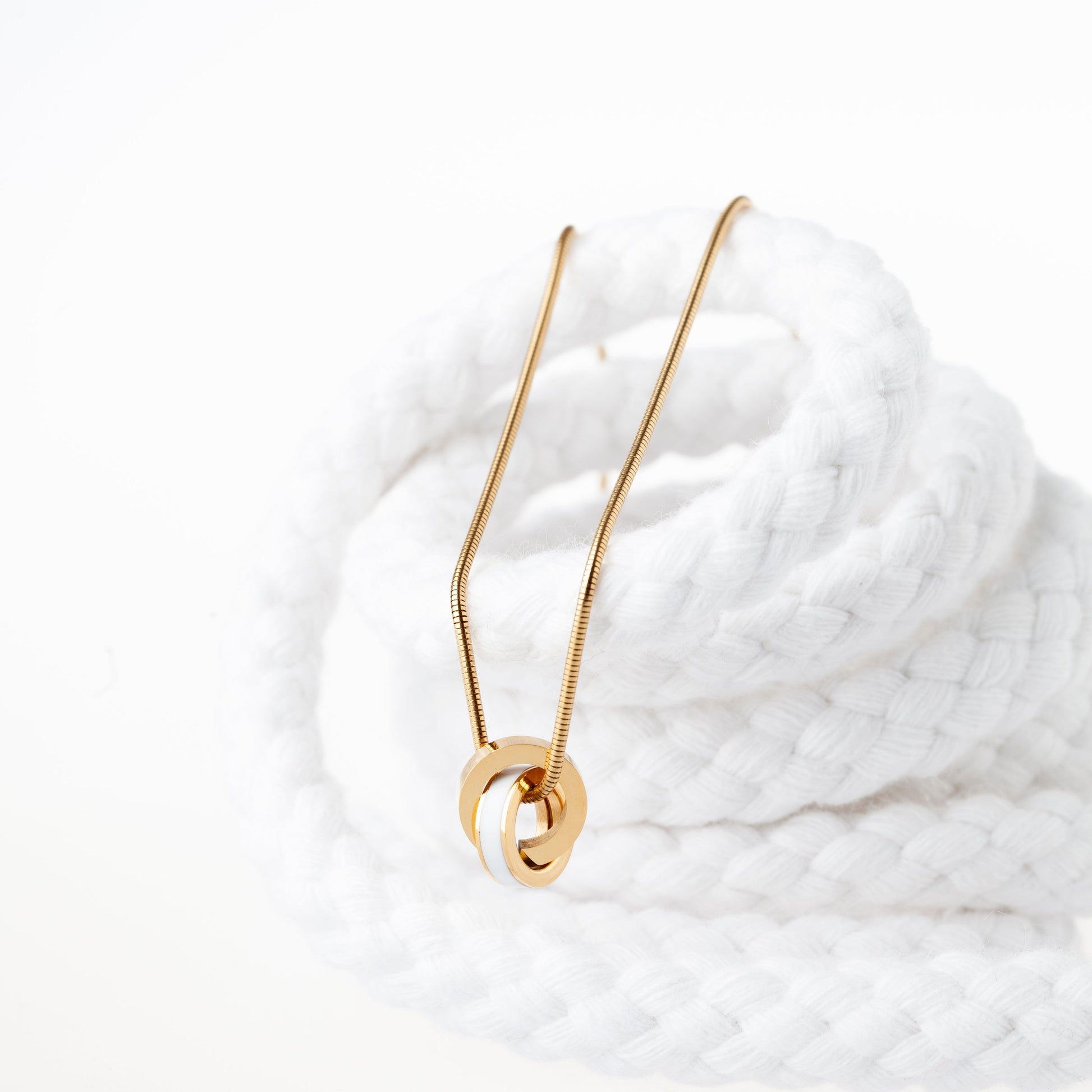 Golden necklace featuring intertwined white chips.