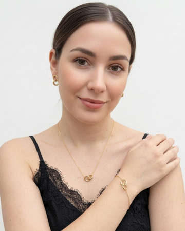 Jason Hyde minimalist gold jewelry set including interlocking link stud earrings and delicate chain bracelet on a model