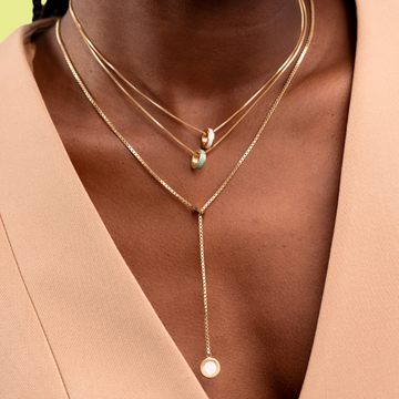 Close-up of a person wearing a layered set of Jason Hyde gold necklaces