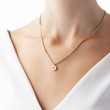 Woman wearing a delicate Jason Hyde necklace with a beige sustainable chip pendant.