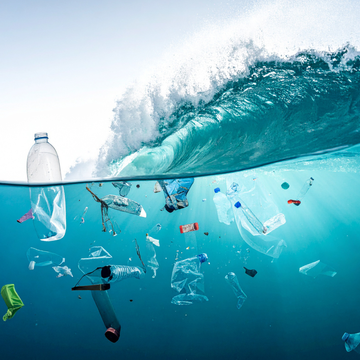 Plastic bottles floating underwater beneath an ocean wave.