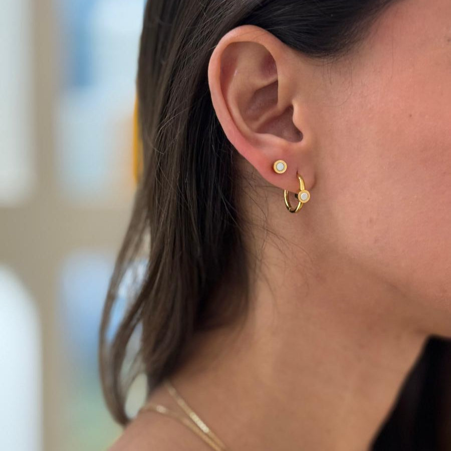 Gold hoop earring with white detail and a small gold earring with a white chip