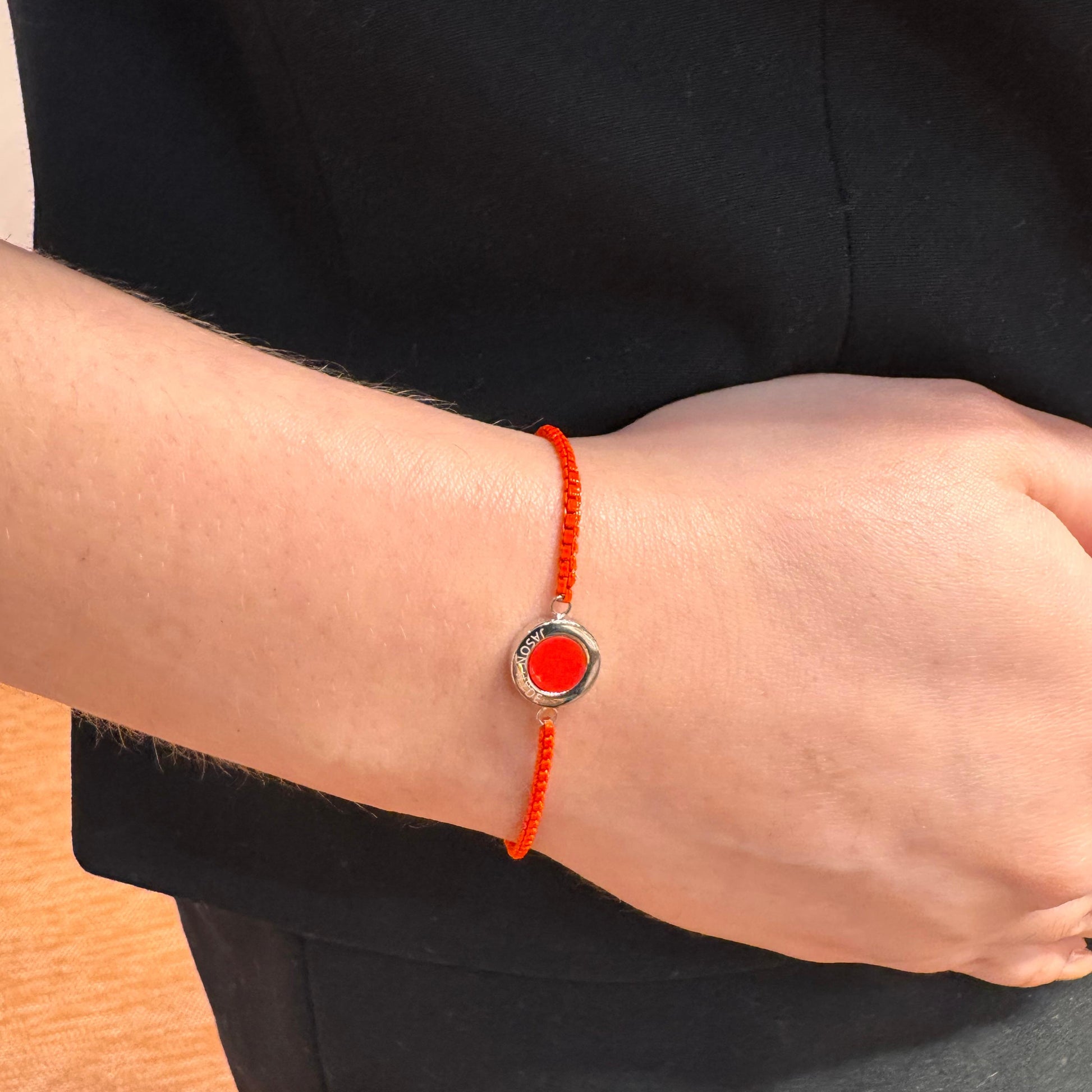Wrist with red string bracelet on a fair skin tone.