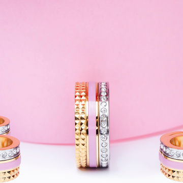 A stacked ring featuring gold studs, a light pink enamel band