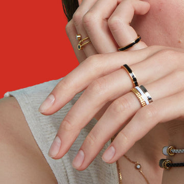 A close-up shot of two hands wearing multiple modern gold rings 