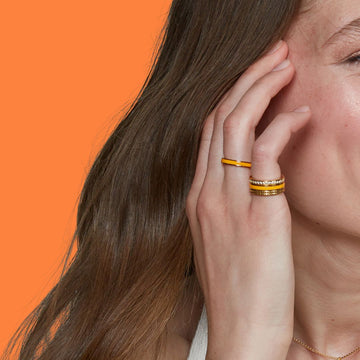 A close-up of a woman's hand touching her hair, showcasing two gold rings
