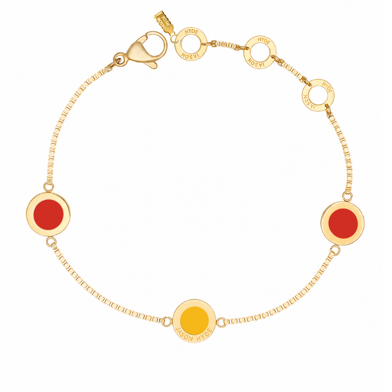 Gold chain bracelet with two red circular charms and one yellow charm.