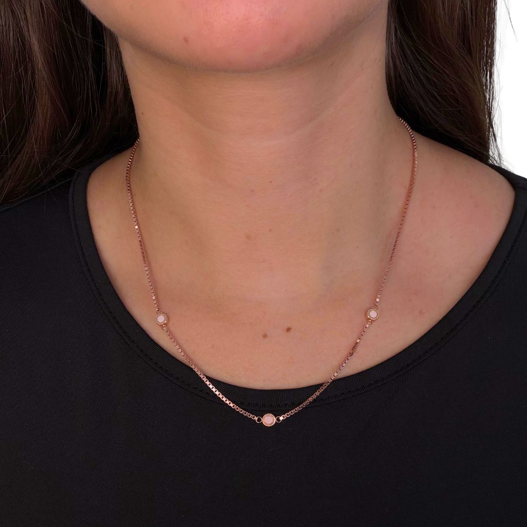 Minimalist rose gold station necklace with pink eco-friendly charms on a black shirt.