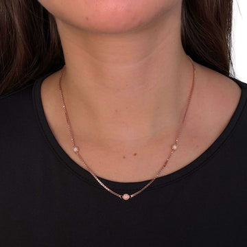 Minimalist rose gold station necklace with pink eco-friendly charms on a black shirt.