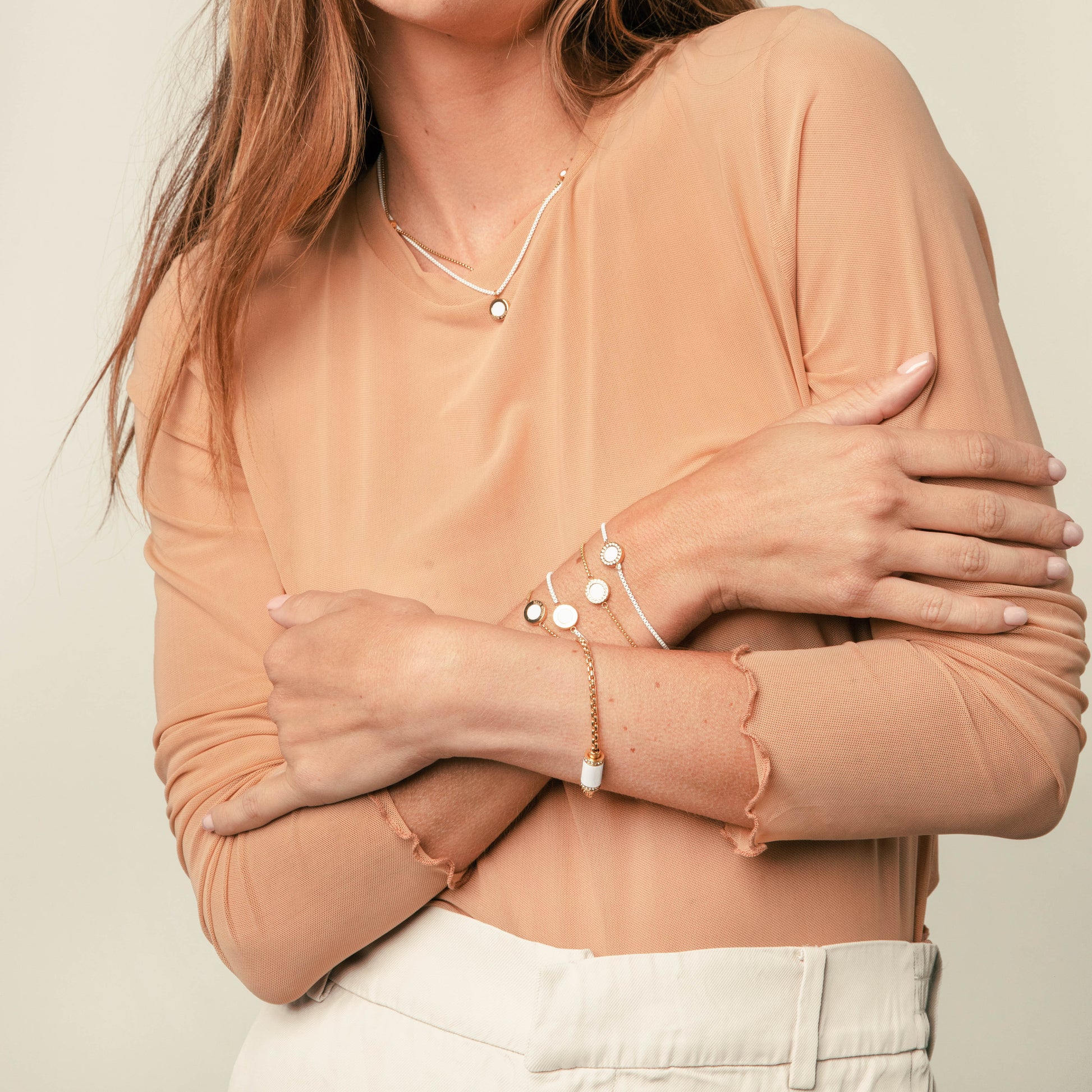 Woman wearing Jason Hyde gold and white jewelry set: necklace and bracelets.