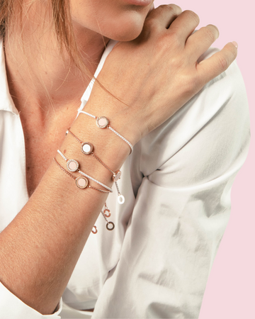 Close-up of a person's wrist wearing a layered set of Jason Hyde rose-gold bracelets