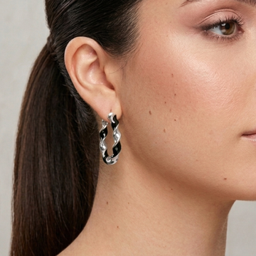 Silver twisted hoop earring with recycled black plastic inlay worn by a model.