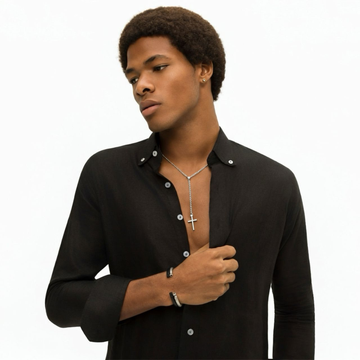 Man in a black button-down shirt wearing a silver cross lariat necklace