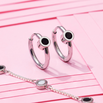 Pair of silver huggie hoop earrings with circular black enamel studs and a matching silver box chain bracelet