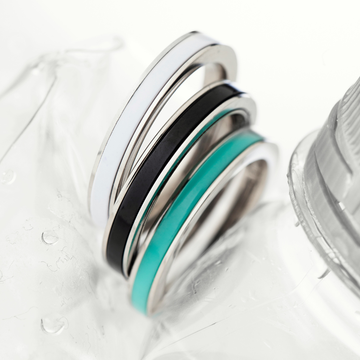 Stacked silver rings with white, black, and teal enamel details