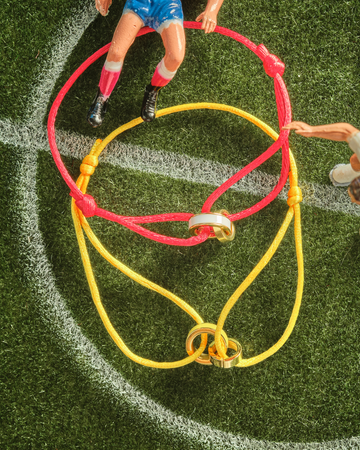 An overhead view of two JASON HYDE cord bracelets on a miniature soccer pitch.