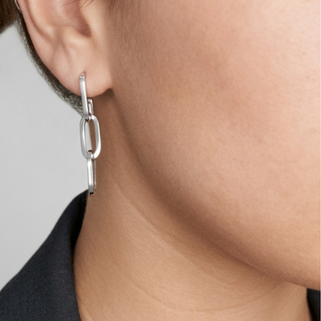 Close-up of a person wearing a sustainable stainless steel oval link drop earring