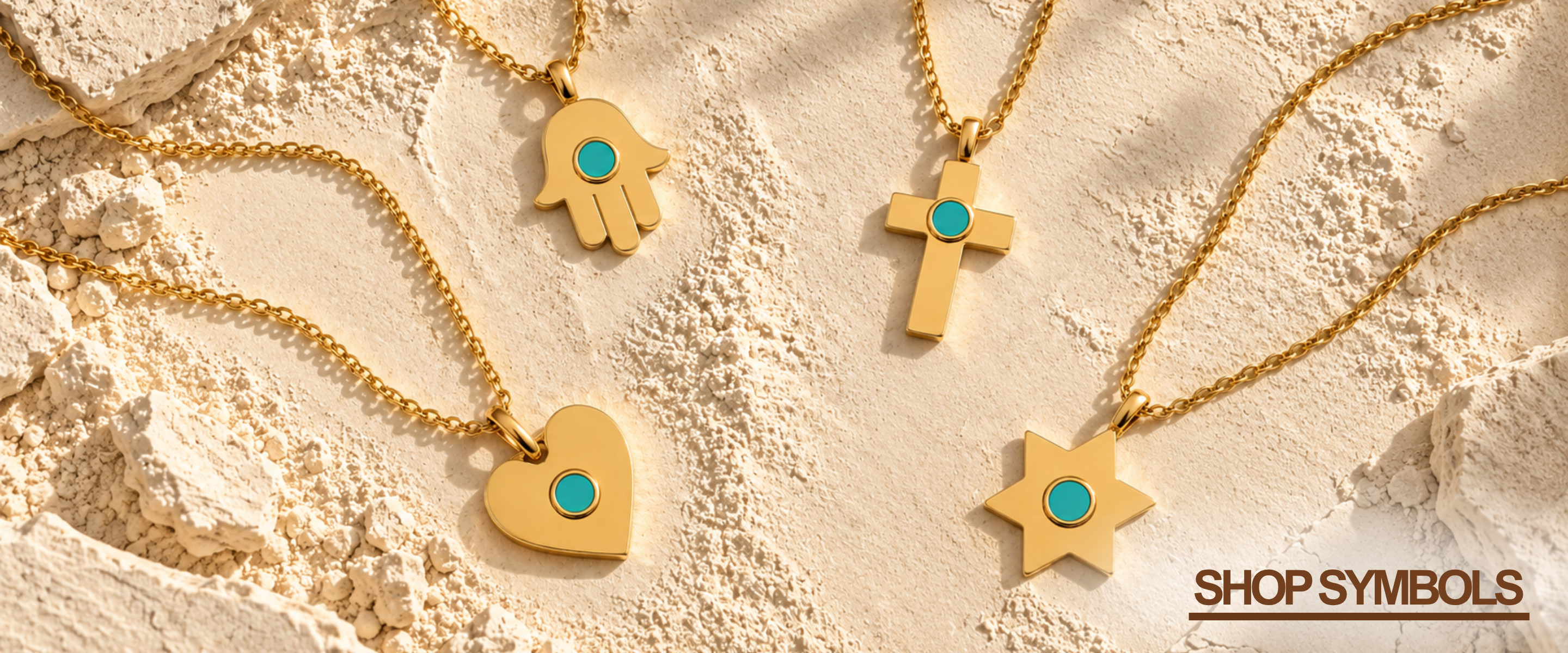 Four gold-tone symbol necklaces laid out on a textured beige surface: a hamsa hand, a cross, a heart, and a star, each with a small turquoise plastic chip center. The text 'SHOP SYMBOLS' appears in the bottom right corner.