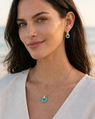 Model wearing a necklace and matching turquoise hoop earrings.