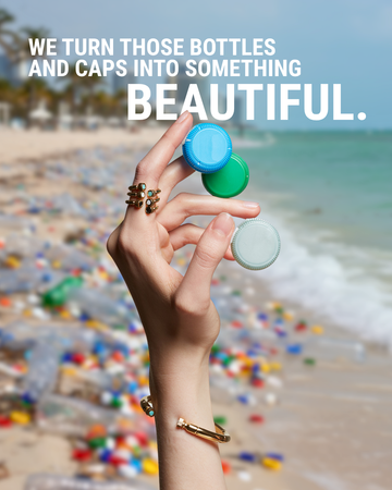 Hand wearing Jason Hyde gold rings holding plastic caps over a polluted beach backdrop. 