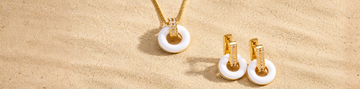 Jason Hyde gold and white pendant necklace with matching drop earrings on sand.
