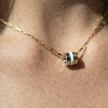 Jason Hyde eco-friendly necklace with a white charm and gold textured barrel details.