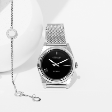 A silver Jason Hyde watch with a black dial and mesh strap