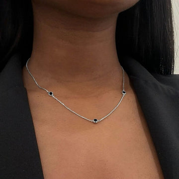 Adjustable silver box chain necklace with black circular elements.