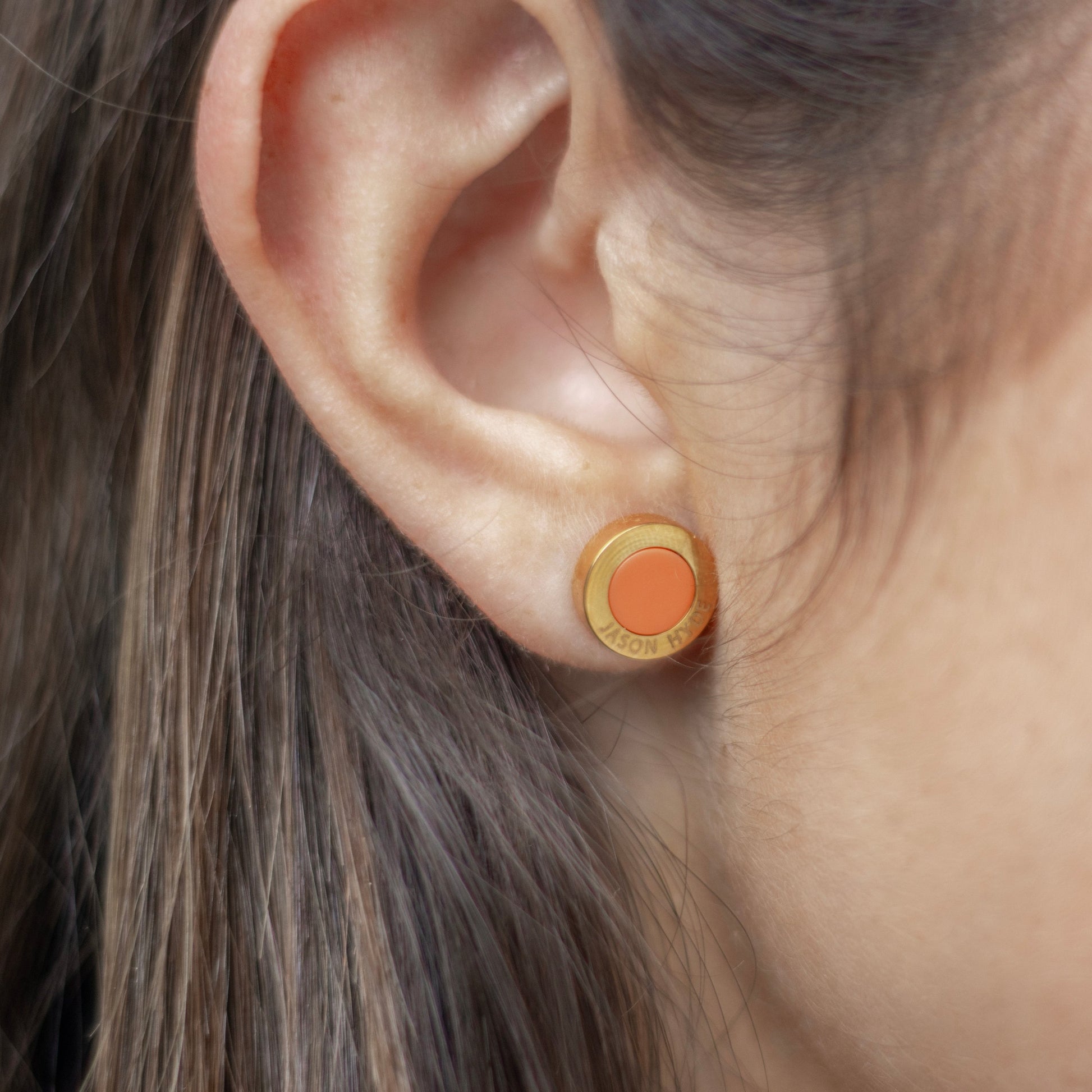 An ear with an orange chip earring by Jason Hyde