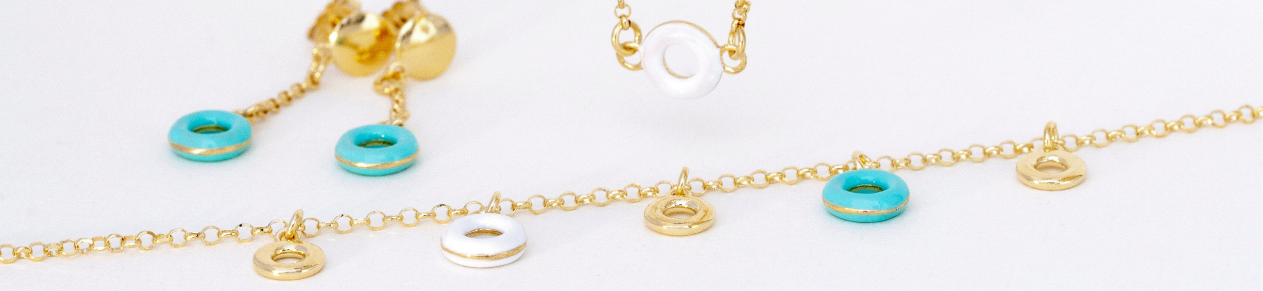 Gold chain necklace with white teal and gold ring charms Matching earrings and a shorter necklace are visible