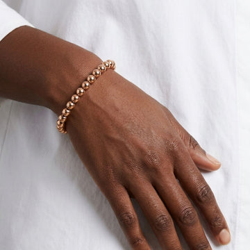 Jason Hyde 18k gold bead stretch bracelet on a model's wrist with a white shirt.