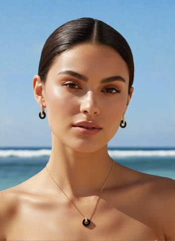 extra-img-A direct portrait of a woman wearing matching black and gold circle jewelry by the sea.
