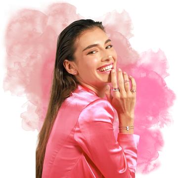 A smiling woman in a shiny pink blazer wearing Jason Hyde jewelry