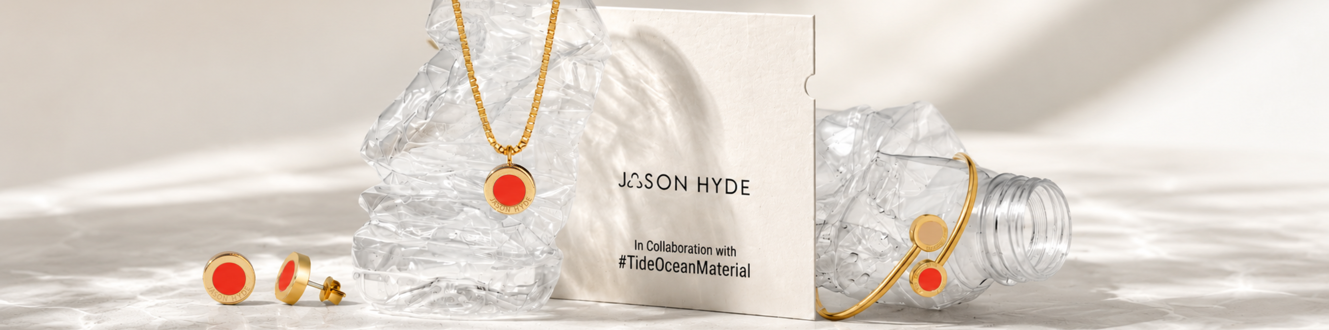 Gold and coral red eco-friendly jewelry set displayed with plastic bottles 